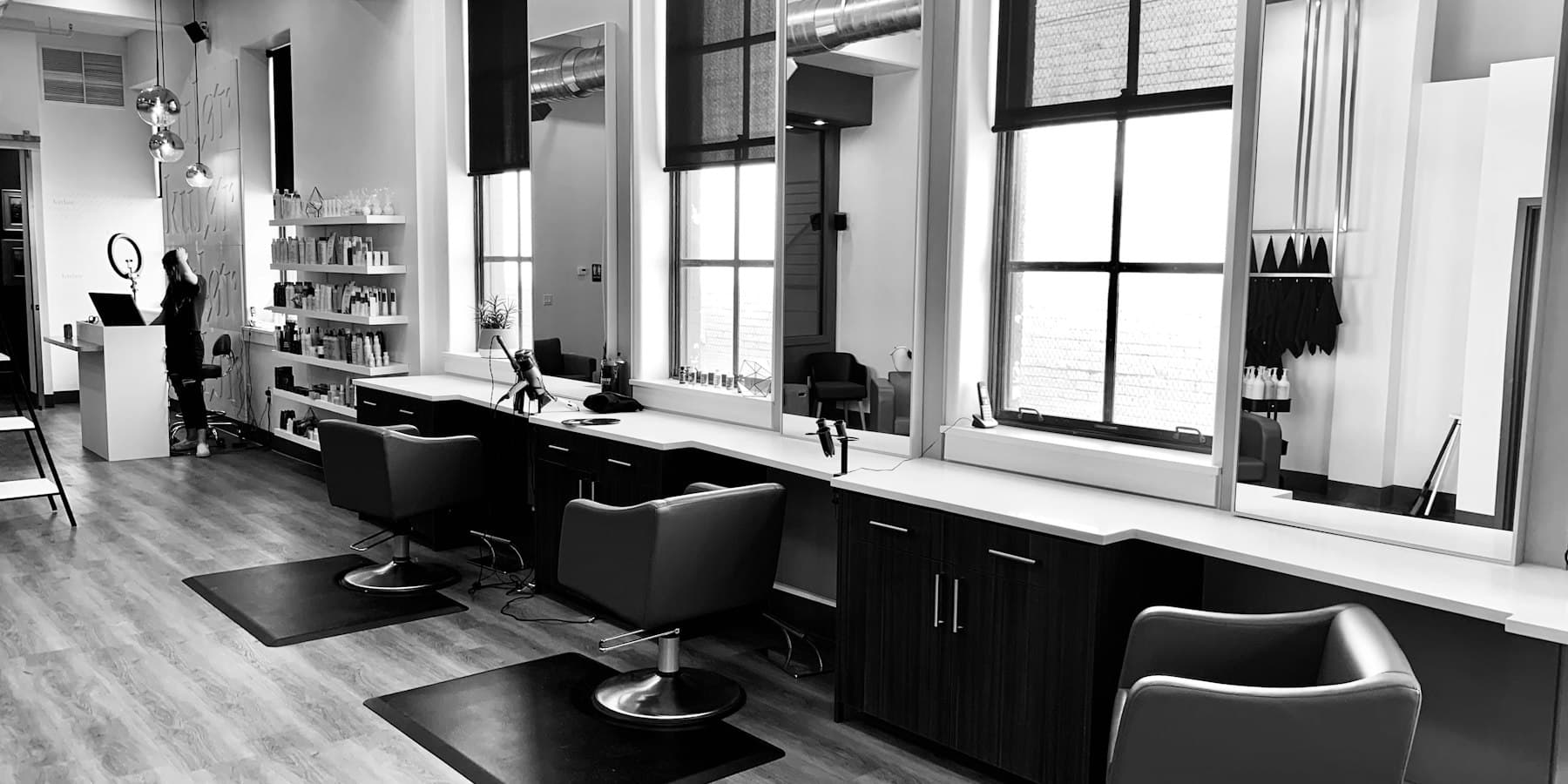 A spacious salon floor with styling chairs and tall windows